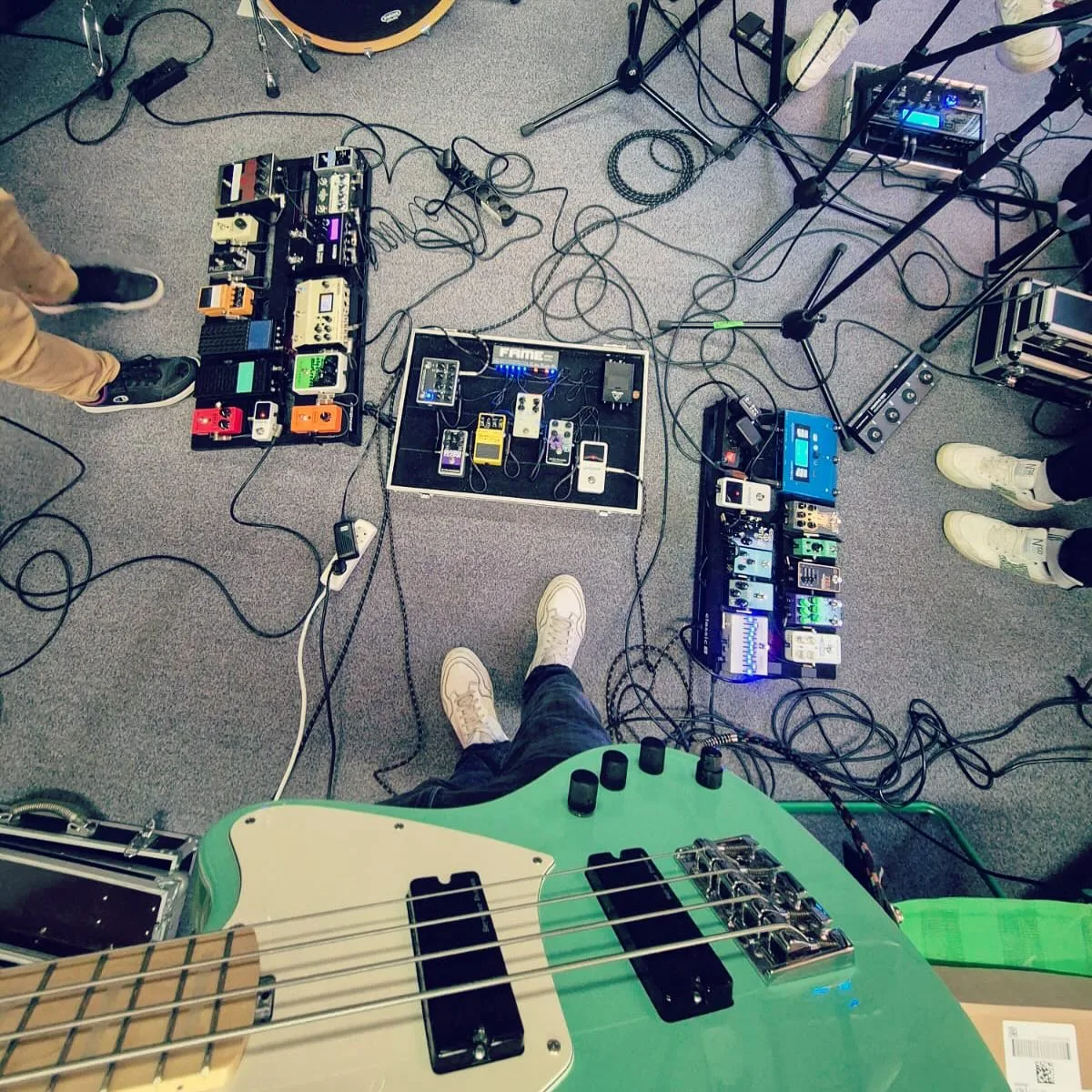 Blick über einen grünen Bass auf Pedalboards im Proberaum